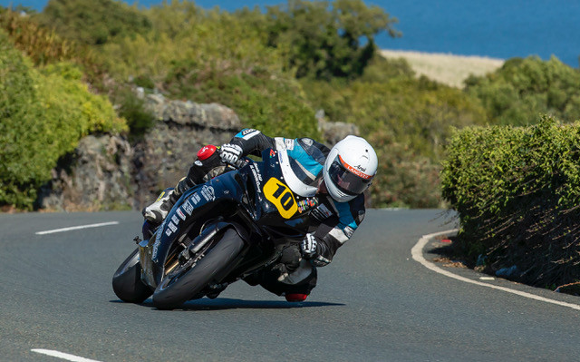 Stephen Smith on motorbike, number 10, leaning into a left hand bend with left knee close to road.
